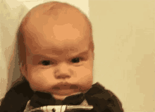 a baby making an angry face with a pair of scissors in his hand