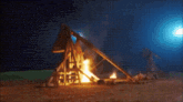 a pixel art drawing of a man sitting on a rock in front of a fire at night