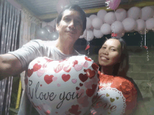 a man and a woman are holding balloons that say i love you