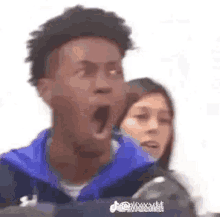 a man is yawning while riding a roller coaster with a woman in the background .