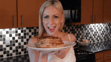 a woman is holding a plate of pancakes in her hands