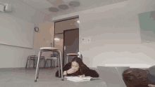 a girl laying on the floor in a classroom with a book on the floor