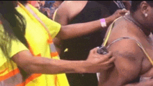 a woman in a yellow vest is adjusting a woman 's bra straps .