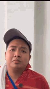 a man wearing a hat and a red shirt is standing in front of a wall .