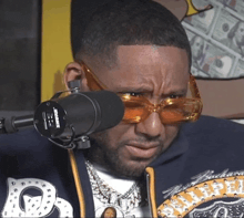 a man wearing sunglasses and a shure microphone makes a funny face