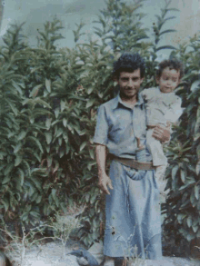 a man in a blue shirt is holding a small child in his arms