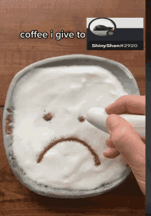 a person drawing a sad face on a bowl of coffee