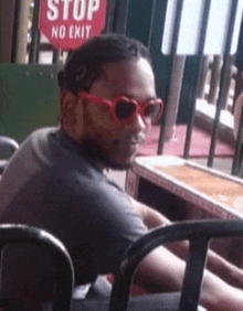 a man wearing sunglasses is sitting at a table in front of a stop sign .