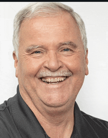 a man with gray hair and a mustache is smiling