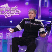 a man sitting in front of a microphone in front of a sign that says ' free ones ' on it