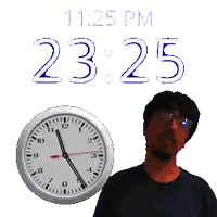 a man stands next to a clock that says 11:25 pm