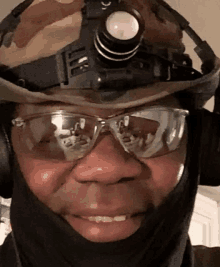 a man wearing a helmet and safety glasses is smiling for the camera