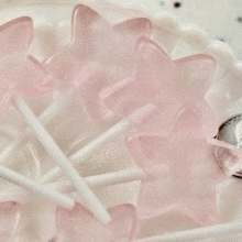 a bunch of pink lollipops in the shape of stars on a white plate .