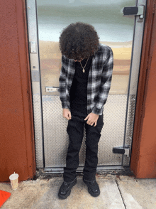 a man in a plaid shirt is standing in front of a door that has a lock on it