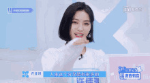 a woman with short black hair is smiling in front of a blue sign that says ' iqiyi ' on it