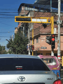 a silver toyota yaris is parked in front of a red traffic light