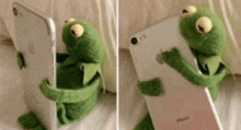 a stuffed kermit the frog is holding a cell phone in its hands .