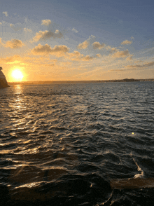 a sunset over a body of water with a tower in the distance