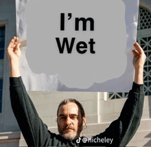 a man holding a sign that says i 'm wet