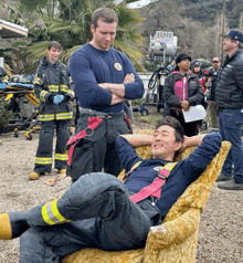 a man in a fireman 's uniform is laying on a couch with his hands behind his head