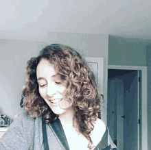 a woman with curly hair wearing a grey shirt