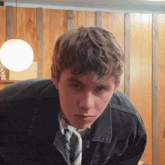a young man wearing a black jacket and a tie
