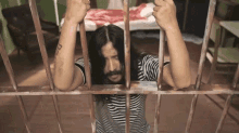 a man with a tattoo on his arm behind bars