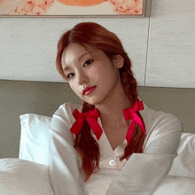 a woman with red hair is laying on a bed with white sheets