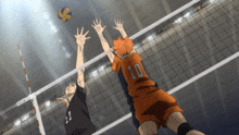 a volleyball player with the number 10 on his jersey is jumping to block another player