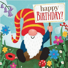 a gnome sitting in a field holding a sign that says happy birthday