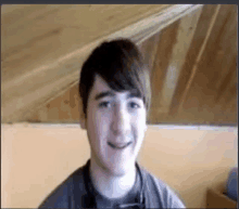 a young man is smiling in a room with a wooden ceiling .