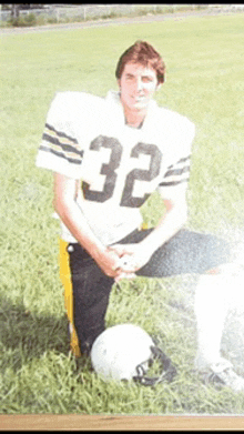 a football player with the number 32 on his jersey is kneeling in the grass