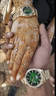 a man is holding a woman 's hand with a rolex watch on it