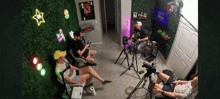 a group of people are sitting in front of a wall that has a neon sign that says arcade