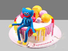 a cake with a blue monster sitting on top of it and the name veronica written on it