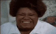 a close up of a woman making a funny face while wearing glasses and a white shirt .