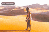 a man is standing in the middle of a sandy desert .