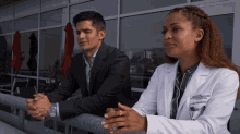 a man in a suit and a woman in a lab coat are sitting next to each other on a balcony