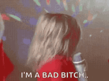 a woman in a red dress is holding a microphone and saying `` i 'm a bad bitch '' .