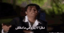 a man in a suit and white shirt is making a funny face in arabic .