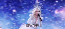 a woman in a white dress is singing into a microphone with the words hey you written below her