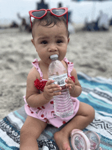 a baby wearing red heart shaped sunglasses is drinking from a bottle of water