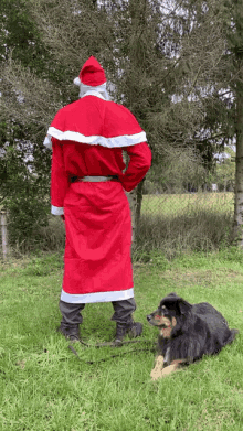 a man dressed as santa claus stands next to a dog on a leash