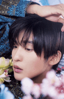 a close up of a young man 's face with flowers in the background