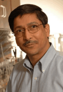 a man with glasses and a mustache wearing a blue shirt