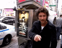 a man standing in front of a telephone booth with a sign on it that says ' a man ' on it