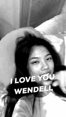 a black and white photo of a woman laying on a bed with the words `` i love you wendell '' written on her face .