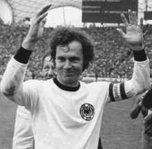 a black and white photo of a soccer player waving at the crowd .