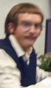 a blurry photo of a man wearing glasses and a blue vest