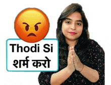 a woman is holding her hands together in front of a sign that says thodi si shame karo .